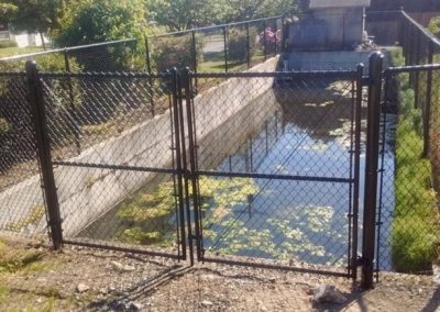 Black chain link at residential area retention pond with double swing gate